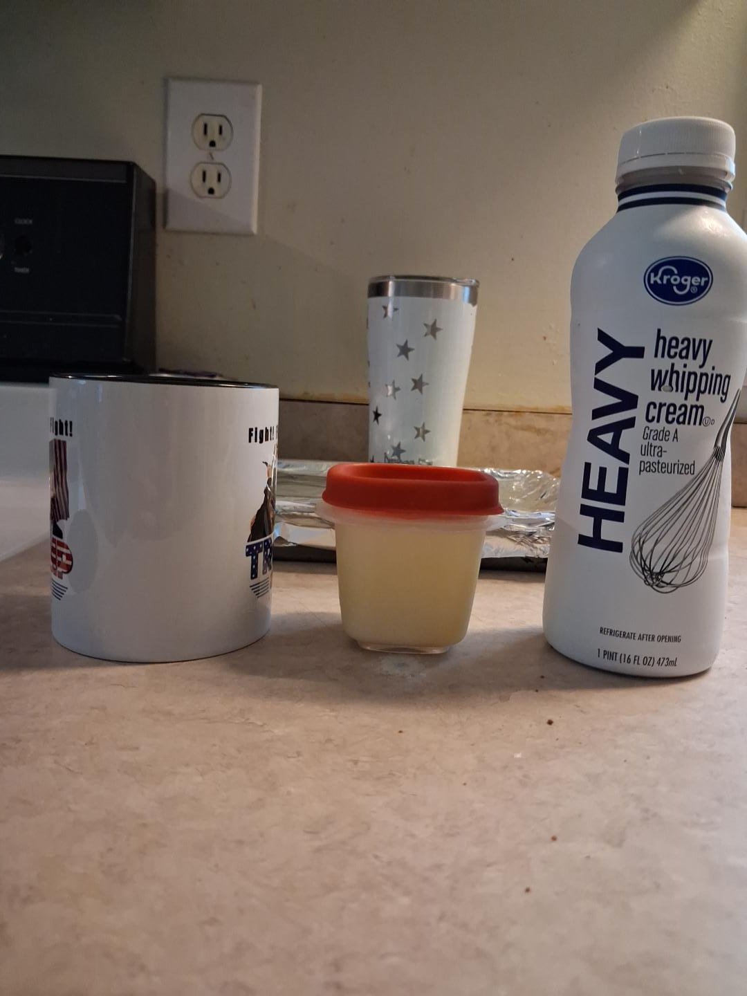 Bottle of heavy whipping cream beside a small container of Ruthlynn’s homemade butter on the kitchen counter