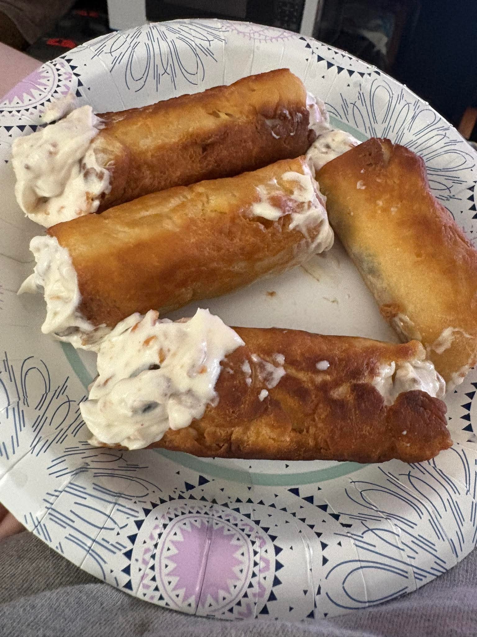 Golden pastry rolls filled with cream on a paper plate