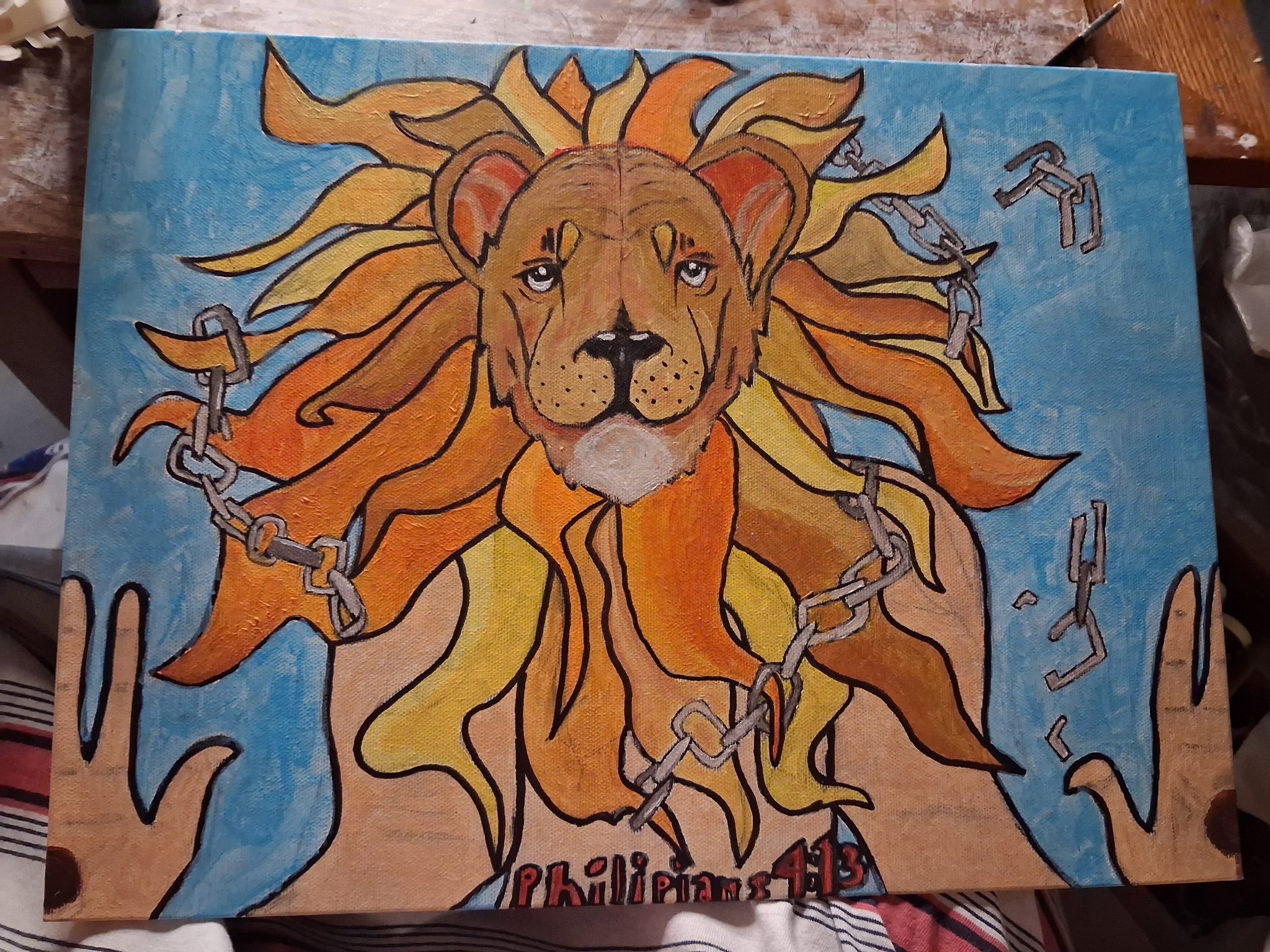 Lion of Judah painting of a golden lion with broken chains woven through its mane and Christ's pierced hands, on a blue background, with Philippians 4:13 painted along the bottom