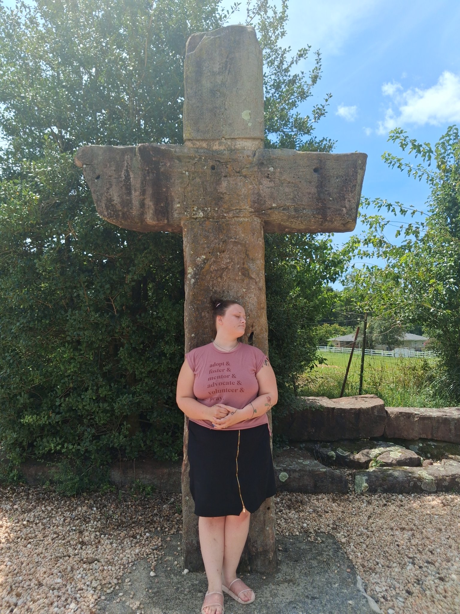 Woman standing beneath a large stone cross at Stonehenge Kentucky